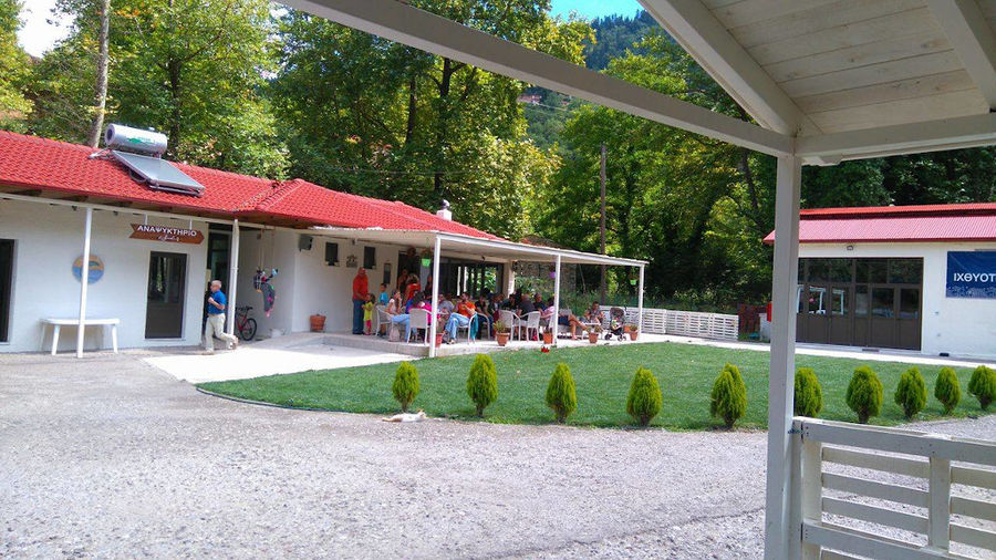 far view of tourists sitting on tables outside at Fresko's café and green lawn in the front